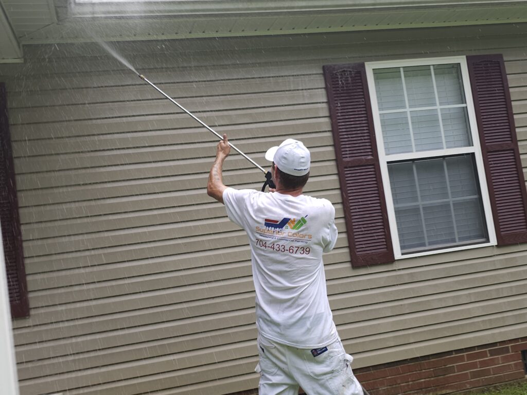 superior colors worker pressure washing the side of a house