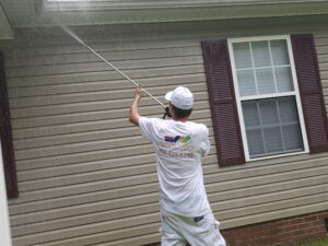 superior colors worker pressure washing the side of a house